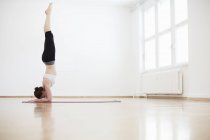 Side view of woman in exercise studio doing handstand — Stock Photo