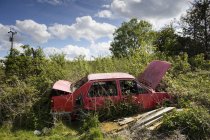 Abandonado coche rojo abierto en el páramo durante el día - foto de stock