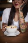 Mulher tatuada com xícara de chocolate quente — Fotografia de Stock