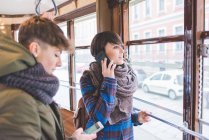 Two sisters riding cable car, using smartphones — Stock Photo