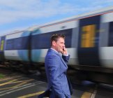 Geschäftsmann steht mit Smartphone an Bahnübergang — Stockfoto