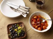 Vista superior da mesa com tigela de azeitonas pretas e tigela de tomates — Fotografia de Stock