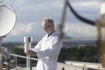 Male meteorologist monitoring meteorological equipment at rooftop weather station — Stock Photo