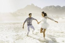 Paar läuft und planscht im sonnenbeschienenen Meer, Kapstadt, Südafrika — Stockfoto