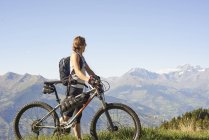 Mujer ciclista de montaña con vistas al paisaje de montaña, Valle de Aosta, Aosta, Italia - foto de stock