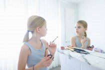 Bedroom mirror image of girl with make up brush staring at herself — Stock Photo
