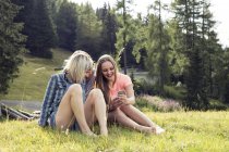Three female adult friends looking at smartphone in field, Sattelbergalm, Tirol, Austria — Stock Photo