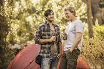 Due campeggiatori maschi che chiacchierano e bevono birra nella foresta, Deer Park, Città del Capo, Sud Africa — Foto stock