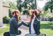 Молоді чоловіки хіпстер близнюки з червоними бородами тремтять руками в парку — стокове фото