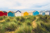 Vista trasera de una fila de cabañas de playa multicolores en dunas de arena, Southwold, Suffolk, Reino Unido - foto de stock