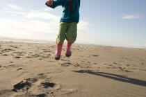 Молода дівчина стрибає на піщаному пляжі — стокове фото