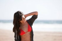 Молода жінка на пляжі з рукою в волоссі — стокове фото