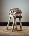 Складені ковдри на маленькому дерев'яному стільці — стокове фото