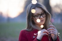 Young woman in park looking at lights in her hand, London, UK — Stock Photo