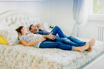Pregnant couple lying on bed smiling — Stock Photo