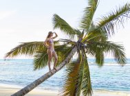 Junge Frau, die aus einer Palme am Strand der Dominikanischen Republik, der Karibik — Stockfoto