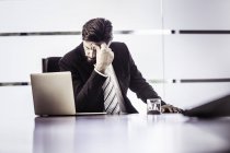 Homme d'affaires stressé avec la main sur le front au bureau — Photo de stock