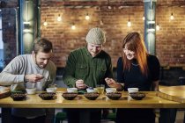 Coffee shop team tasting bowls of coffee and coffee beans — Stock Photo