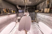 Tischler mit Zimmermannsausrüstung auf Surfbrett in Surfbrett-Werkstatt — Stockfoto