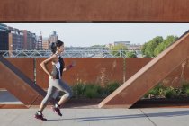 Läuferin läuft auf städtischer Fußgängerbrücke — Stockfoto