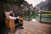 Mujer relajante en silla de madera, Lago di Braies, Alpes Dolomitas, Val di Braies, Tirol del Sur, Italia - foto de stock