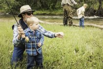 Grand-père enseignant petit-fils comment utiliser la canne à pêche — Photo de stock