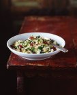 Кус-салат з ложкою в мисці на сільському столі — стокове фото
