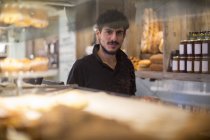 Portrait of young male barista behind cafe counter — Stock Photo