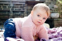 Портрет девочки, ползающей по вязанному одеялу в саду — стоковое фото