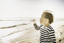Junge am Strand trinkt aus Wasserflasche — Stockfoto