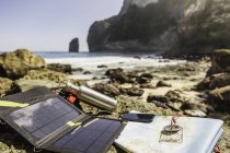 Cargador de batería solar y smartphone en la playa, Costa Sur, Nusa Penida, Indonesia - foto de stock
