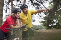 Пара горных велосипедистов с помощью навигации по смартфону в лесу — стоковое фото