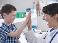 Arzt und Junge machen High Five in Klinik — Stockfoto
