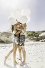 Pareja sosteniendo montón de globos besándose en la playa, Cape Town, Sudáfrica - foto de stock
