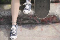 Ноги жіночого скейтбордера зі скейтбордом на кроці — стокове фото