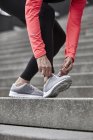 Обрезанный снимок взрослой женщины, тренирующейся на городской лестнице, завязывающей тренерские шнурки — стоковое фото