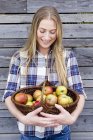 Femme adulte moyenne tenant panier de pommes maison — Photo de stock