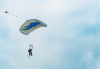 View of tandem parachuting down against cloudy sky — Stock Photo