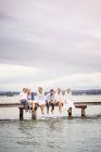 Gruppe von Freunden sitzt in Reihe am Rand der Seebrücke — Stockfoto