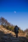 Rückansicht einer Frau, die auf einem Hügel unter blauem Himmel wandert — Stockfoto