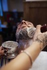 Женщина наносит крем для бритья на бороду мужчины — стоковое фото