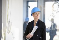 Portrait of businesswoman holding blueprint in new office — Stock Photo