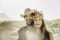 Mid adult couple wearing straw hat and feather headdress on beach, Cape Town, South Africa — Stock Photo