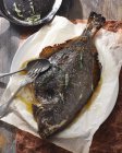 Whole baked flounder with spoon and fork on plate — Stock Photo
