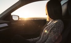 Junge Frau sitzt auf dem Beifahrersitz des Autos und schaut aus dem Fenster — Stockfoto
