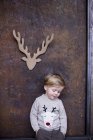 Portrait of young boy, cardboard reindeer cut out on wall behind him — Stock Photo