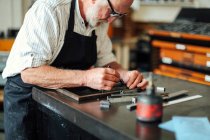 Senior craftsman working on letterpress in print workshop — Stock Photo