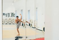 Mirror image of martial artist in gym doing kick — Stock Photo