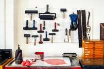 Rolos, tinta e equipamentos na parede na oficina de impressão — Fotografia de Stock