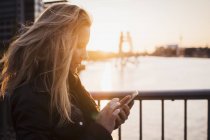 Жінка користується мобільним телефоном на заході сонця (Спре, Берлін, Німеччина). — стокове фото